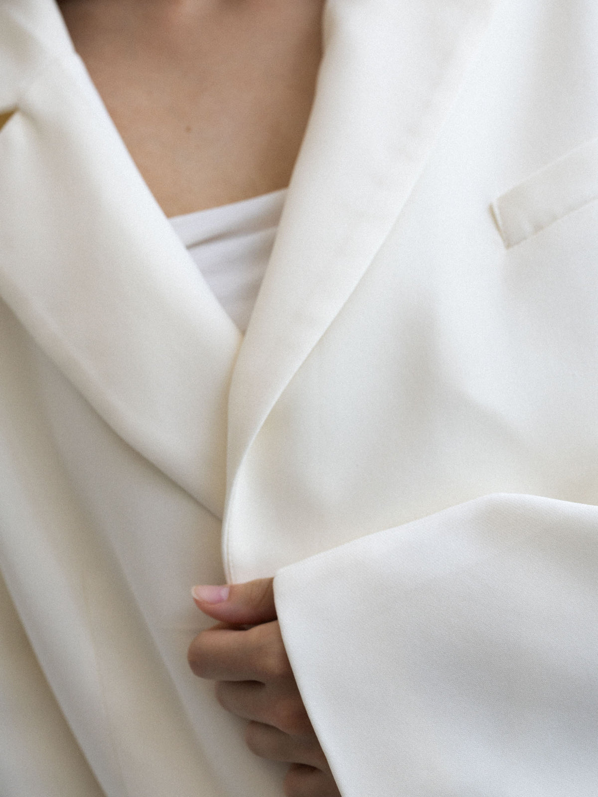 Detal klapy, kołnierza i gładkiej tkaniny marynarki cropped NAIA buttermilk, Marieta Żukowska dla Muuv, dostępna na beetles.shop.