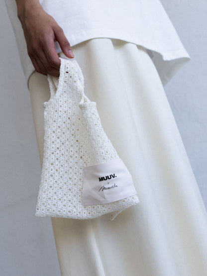 Mini torba ORIA off-white z ażurowej koronki, trzymana w dłoni, z naszywką Muuv x Marieta Żukowska, dostępna na beetles.shop.
