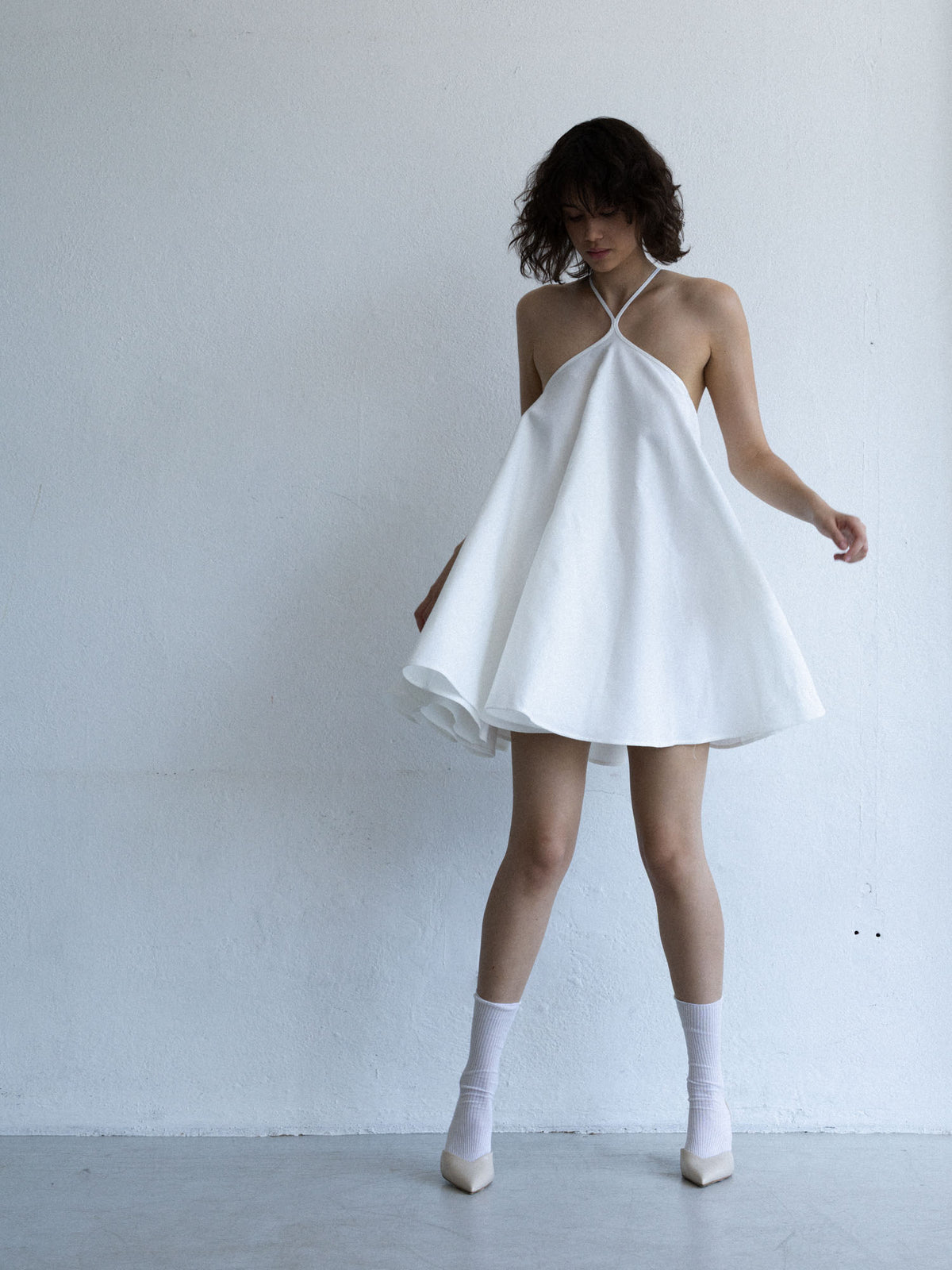 Sukienka mini SOLEA off-white na modelce, trapezowy krój i dekolt halter, kolekcja Mariety Żukowskiej x Muuv, dostępna na beetles.shop.