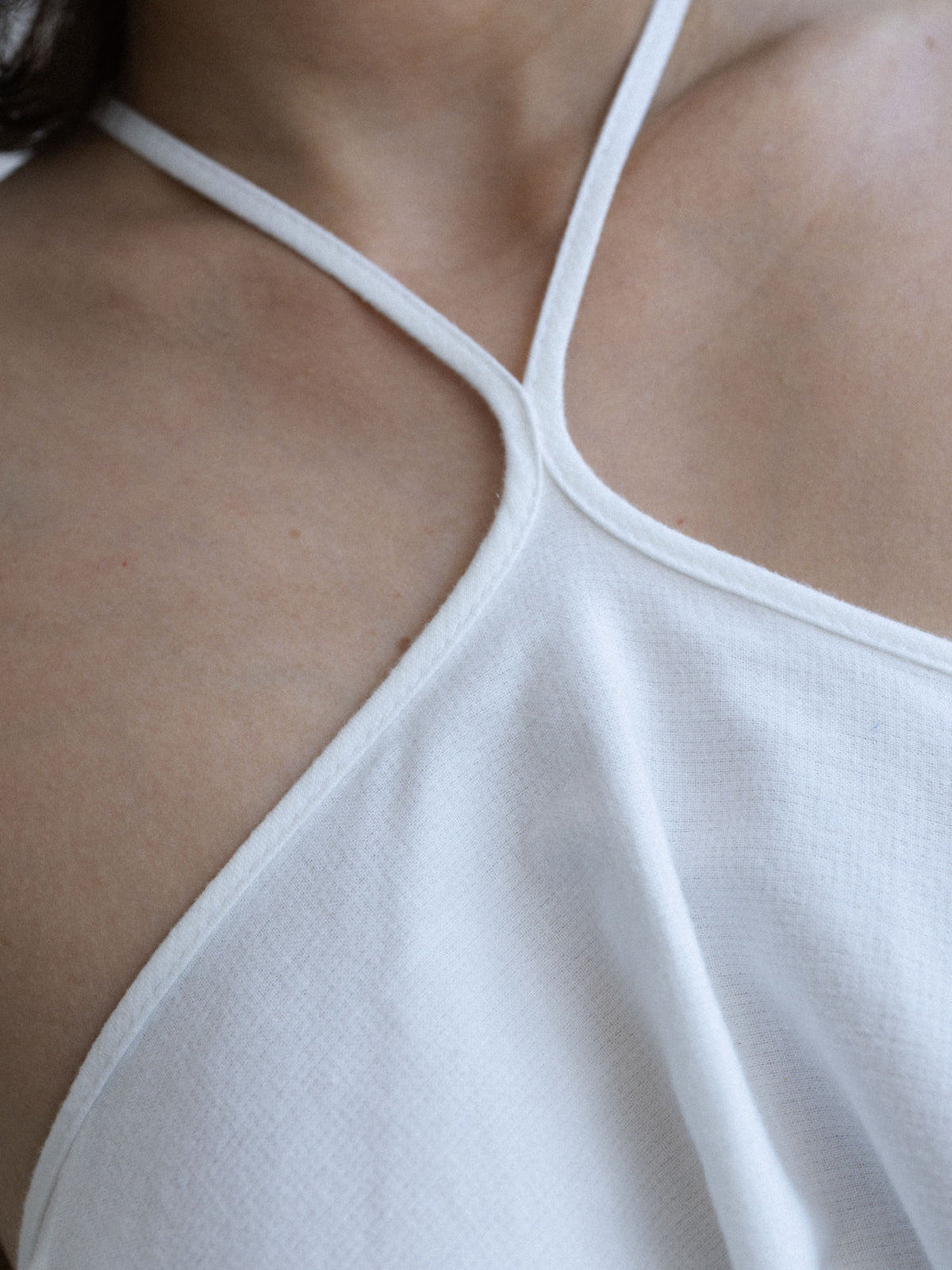 Zbliżenie dekoltu halter sukienki SOLEA off-white o rozkloszowanym kroju, Marieta Żukowska x Muuv, dostępna na beetles.shop.